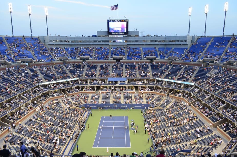 A large tennis court with hundreds of people sitting around
