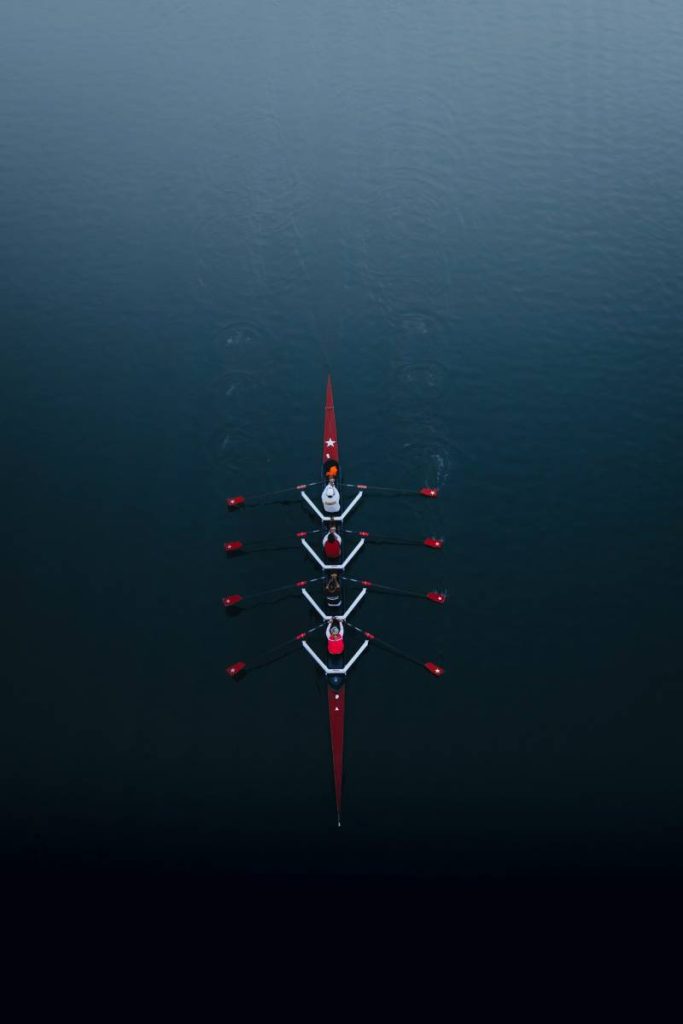 A team of 4 people rowing a boat in a river